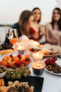 Cozy outdoor dinner party with friends, featuring candle lights and a delicious spread.